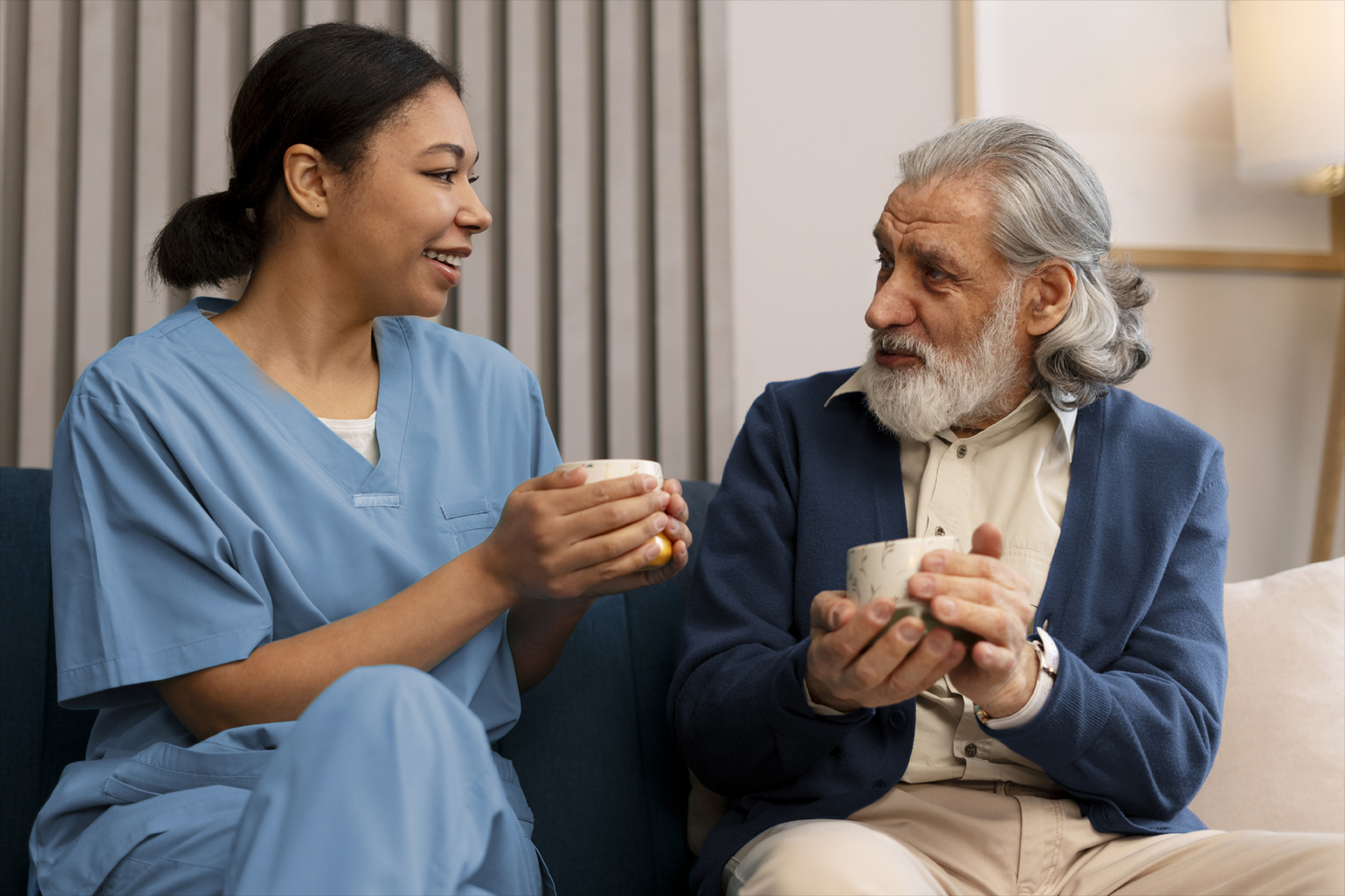 A nurse and a senior man drinking tea together